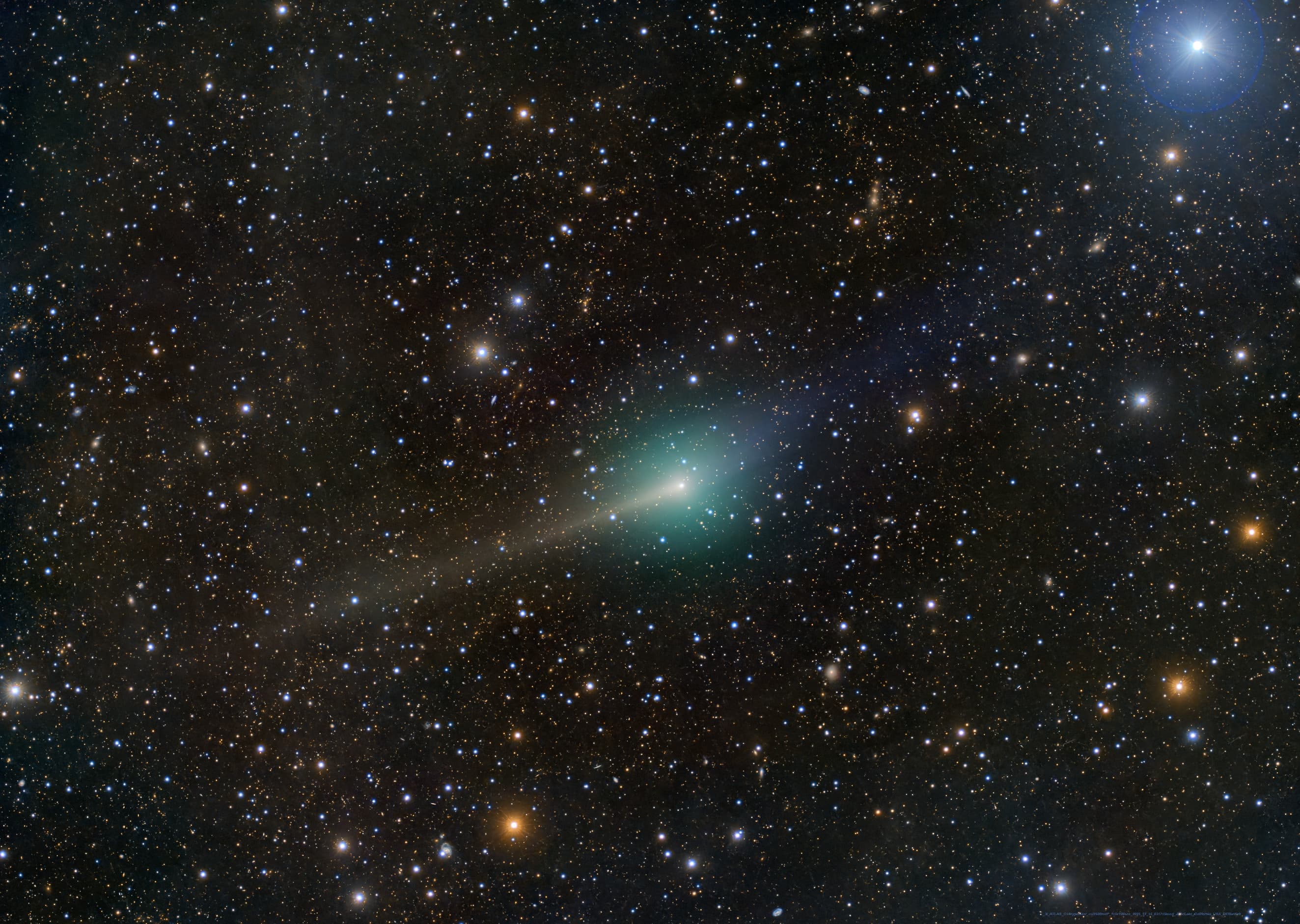 مُذنّب بذؤابة ساطعة ينتشر منها ضوء مخضرّ وخلفه ذيل مصفرّ وأمامه ذيل مزرقّ قبالة خلفيّة من النجوم والأجرام المتفاوتة