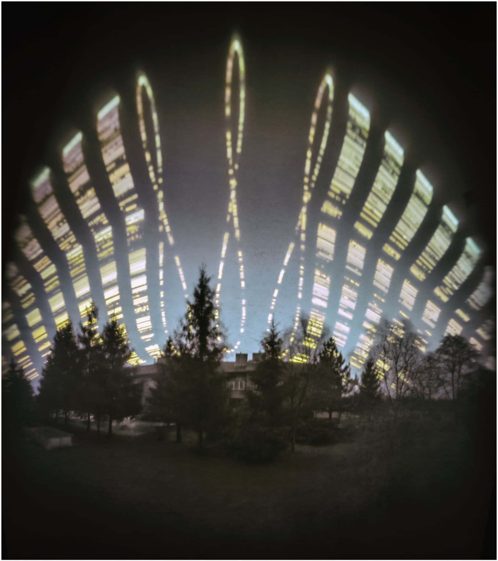 سماء فيها خطوط ساطعة متقطّعة هي أنالِمات وتحتها أبنية وأشجار