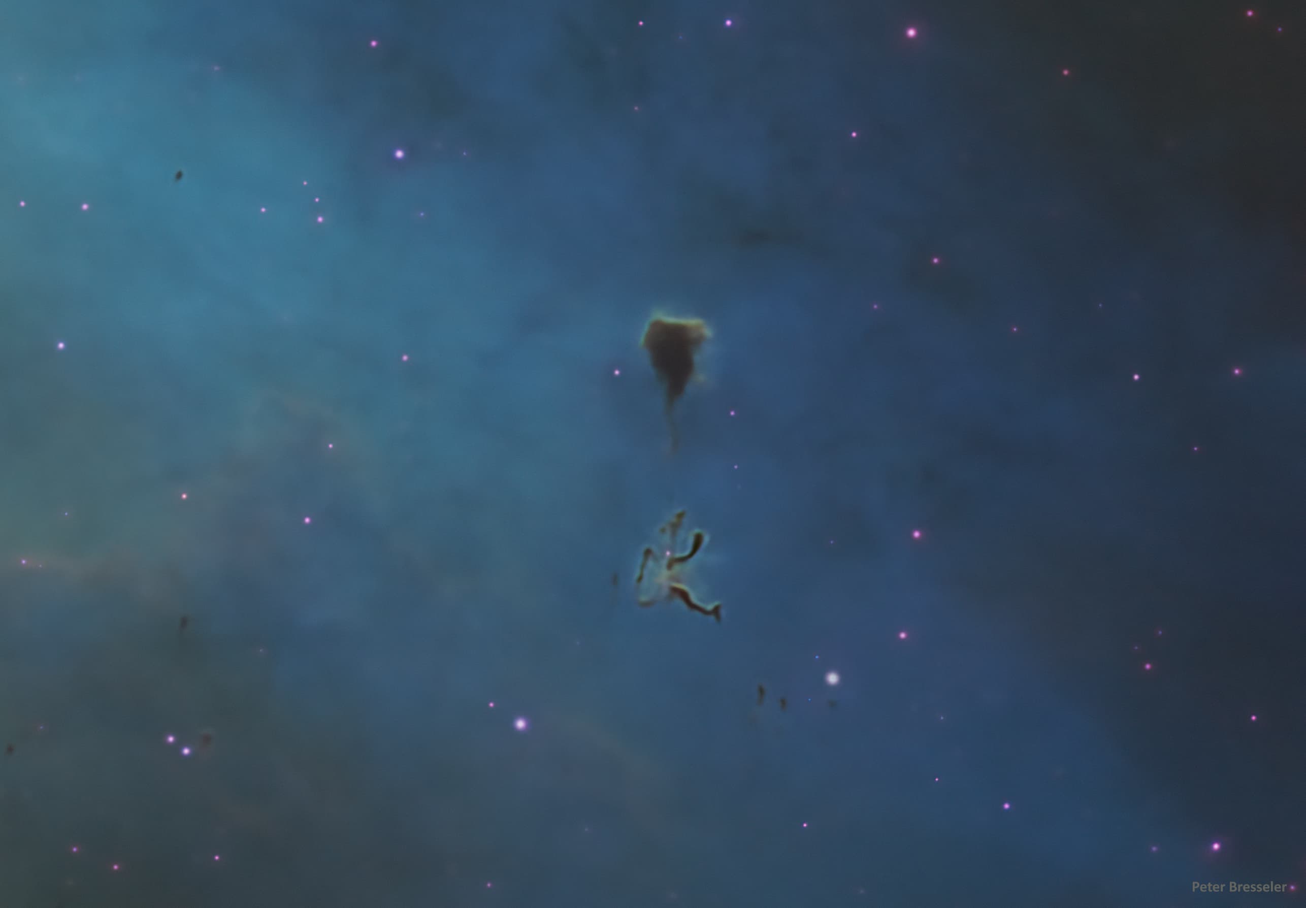 تجمّع غباري داكن يشبه الوتد تحته خيوط من مادّة مشابهة على خلفيّة مزرقّة وأجرام متناثرة تظهر ورديّة اللون