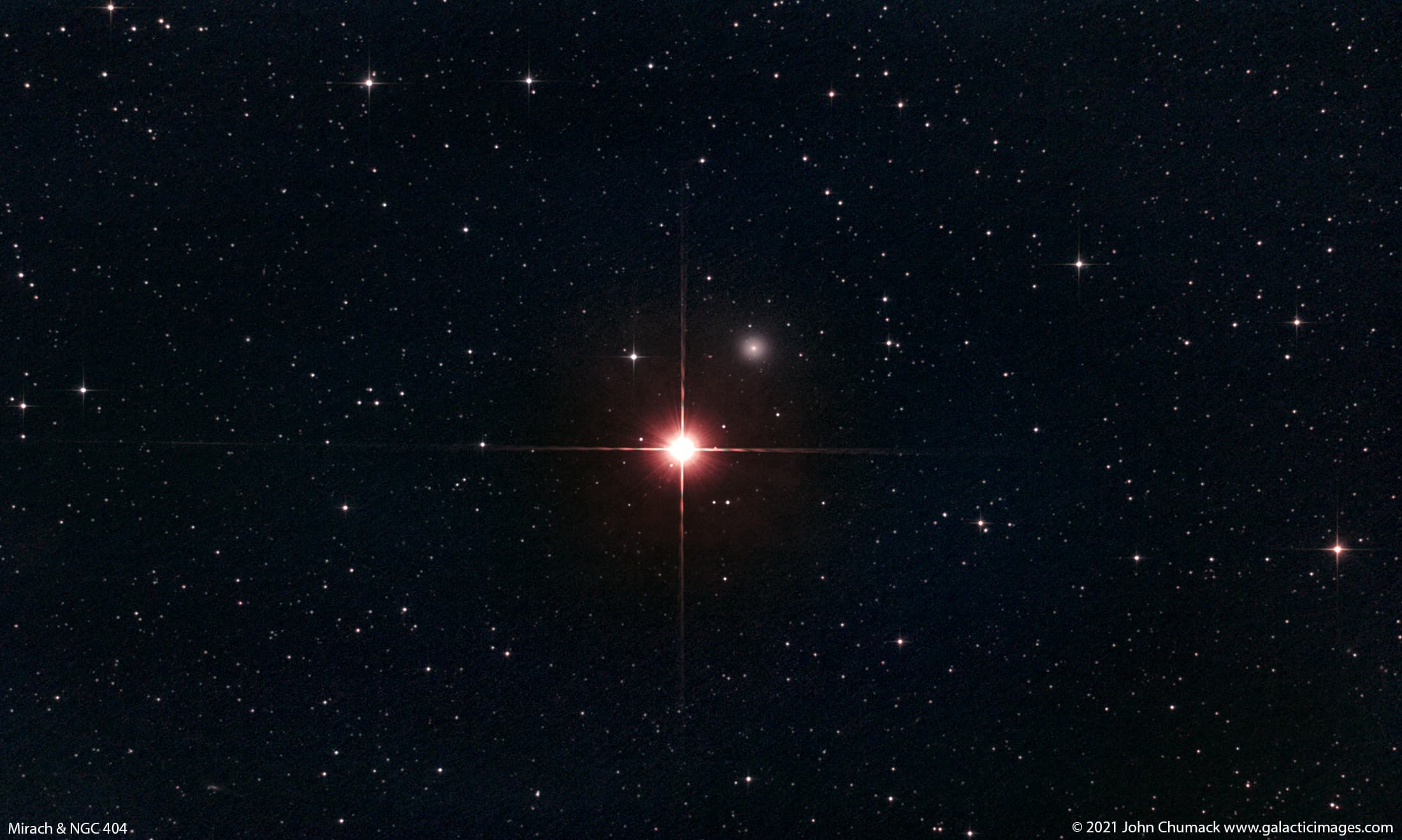 صورة للفضاء العميق تُظهر نجماً ساطعاً ذو انحرافات ضوئية مدببة بالإتجاهات الأربع، بينما تظهر مجرّة زغباء صغيرة بقربه على أعلى اليمين، بينما تتناثر العديد من النجوم على امتداد الصورة