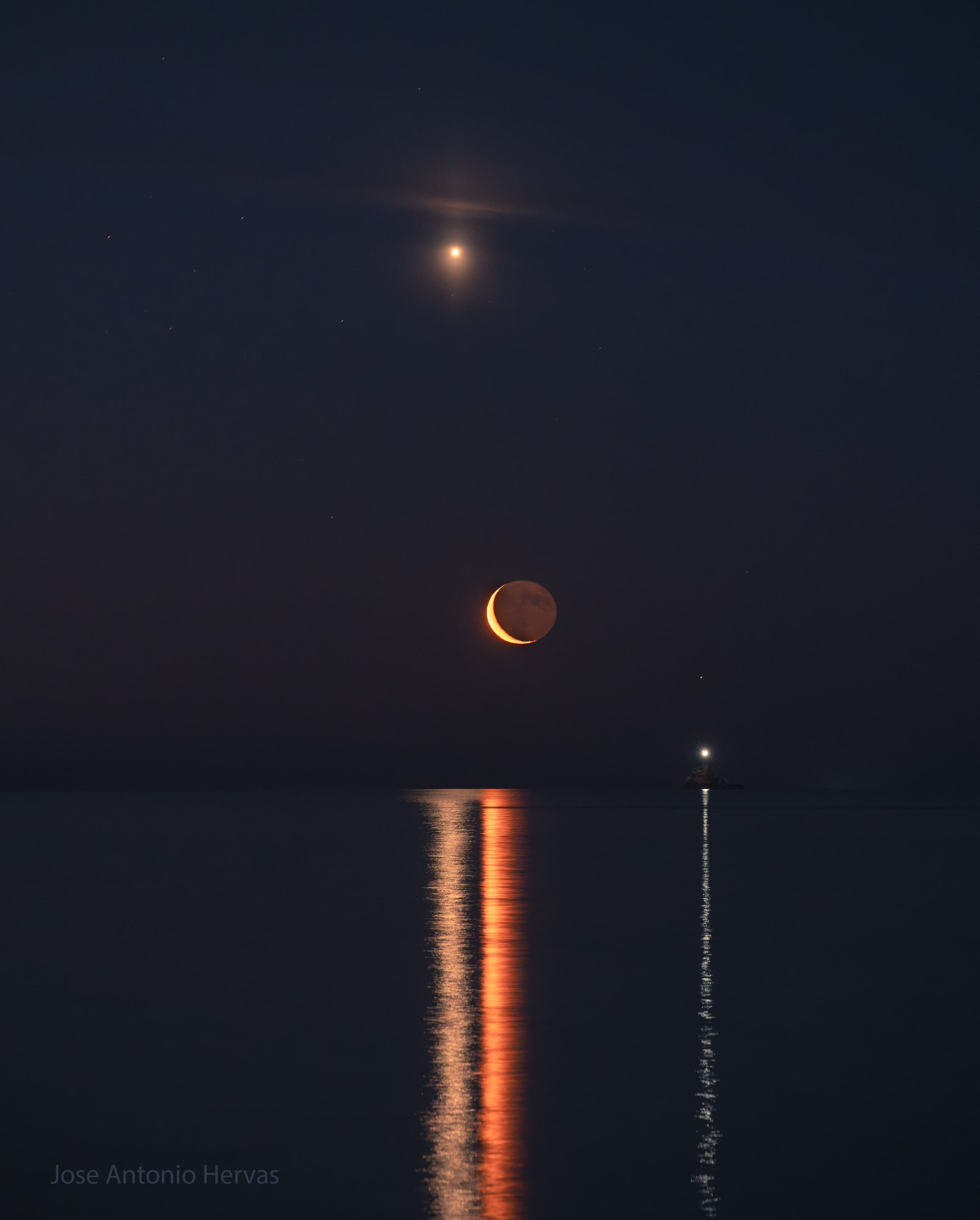 سماء ليل فوق سطح ماء متموّر. يشعّ كوكب الزهرة عالياً بينما يظهر مُشترٍ خافتٌ في أقصى اليسار. يظهر الهلال عند مركز الصورة. تظهر منارة مراكب على اليمين. جميع هذه الأجرام تنعكس كخطوط في ماء المقدّمة.