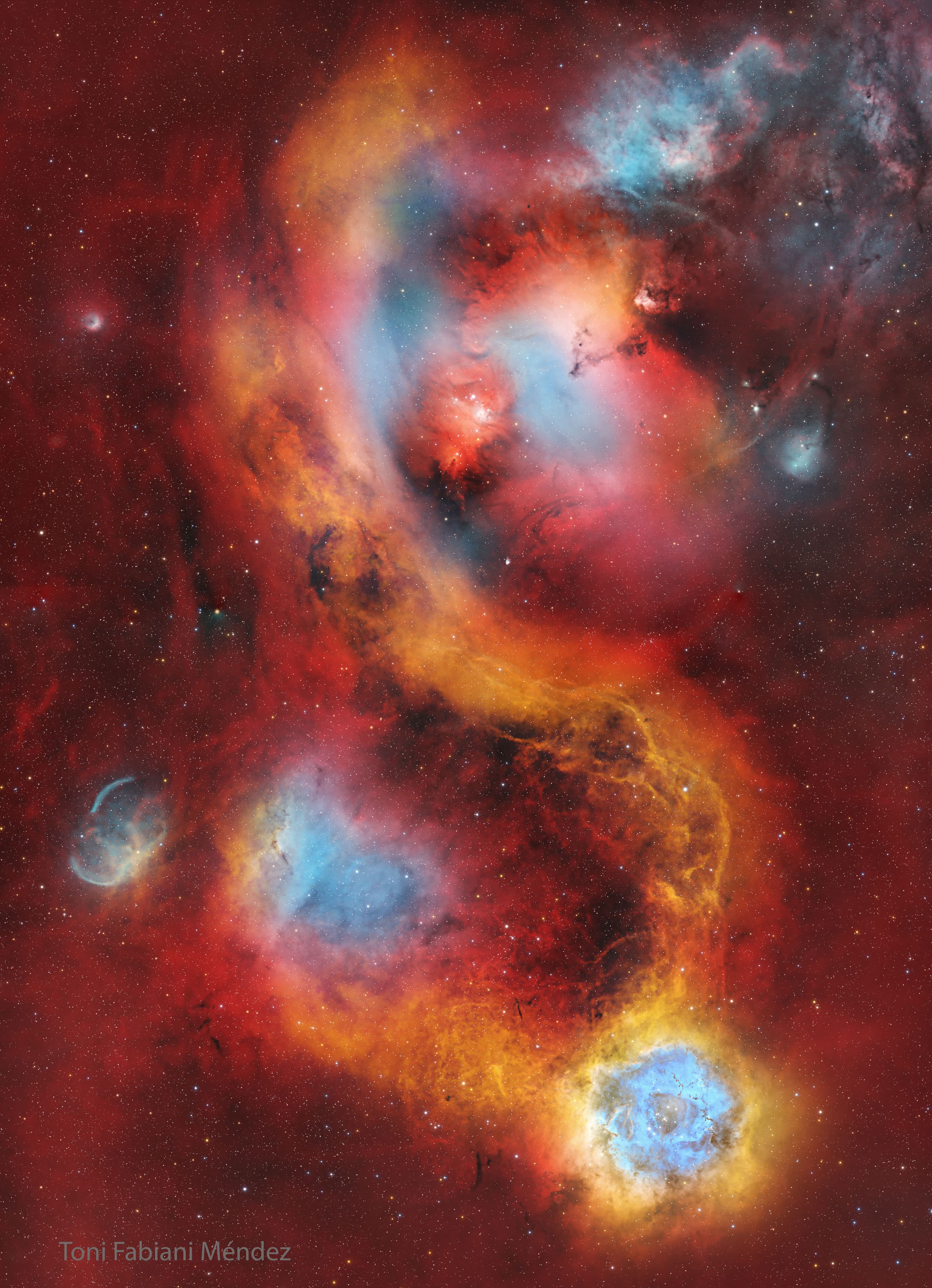 حقل نجومٍ يغطيّه توهّجٌ أحمرٌ فاتح مع وجود عدّة سُدُمٍ حمراء كبيرة قرب المركز. يوجد سديم الوردة الشهير بالأزرق والأبيض قرب أسفل الصورة.