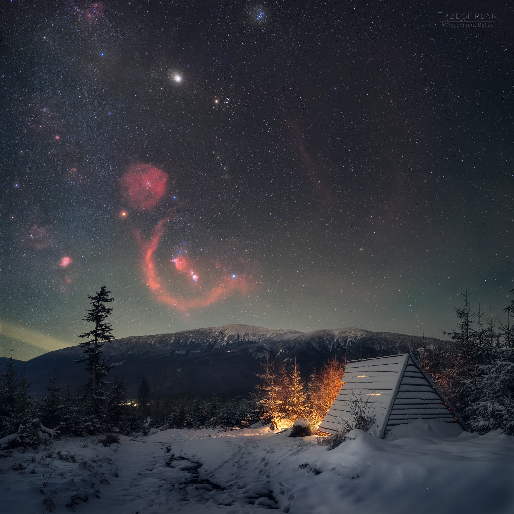 سماء ليل تظهر فيها سدم محمرّة ونجوم كثيرة وتحتها في المقدّمة أرض وكوخ وأشجار تكسوهم الثلوج وخلفهم في الأفق مرتفعات جبليّة