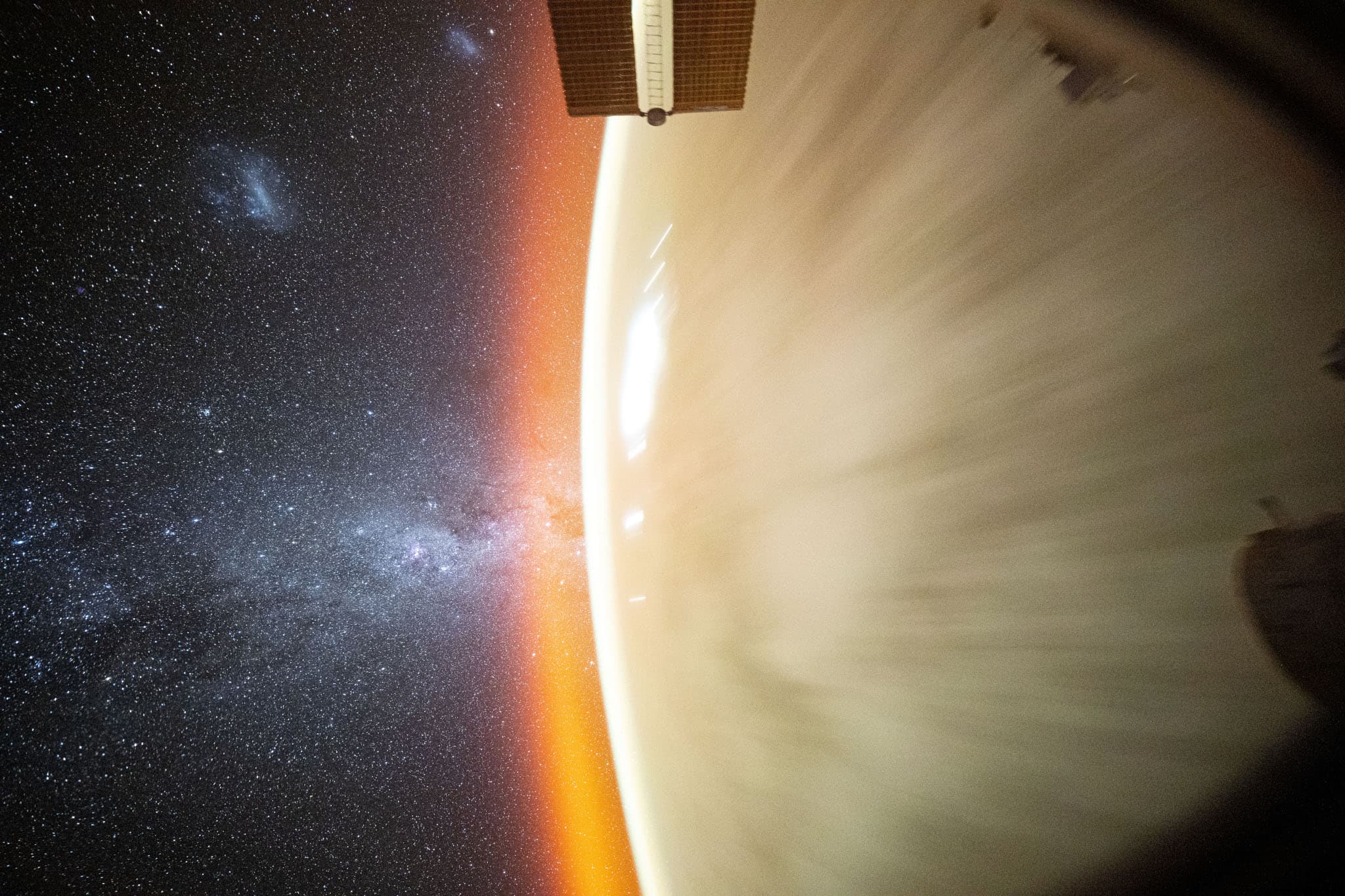 الكُرة الأرضيّة تظهر جزئيّاً مبيضّة مطموسة المعالم بسبب حركة المركبة التي التُقطت منها الصورة والتي تظهر أجزاءٌ منها في الإطار. يظهر على أُفق الأرض توهّجٌ برتقالي فيما تظهر صفحة السماء خلفها بامتداد نطاق درب التبّانة ومجرّتي ماجلّان وآلاف النجوم.